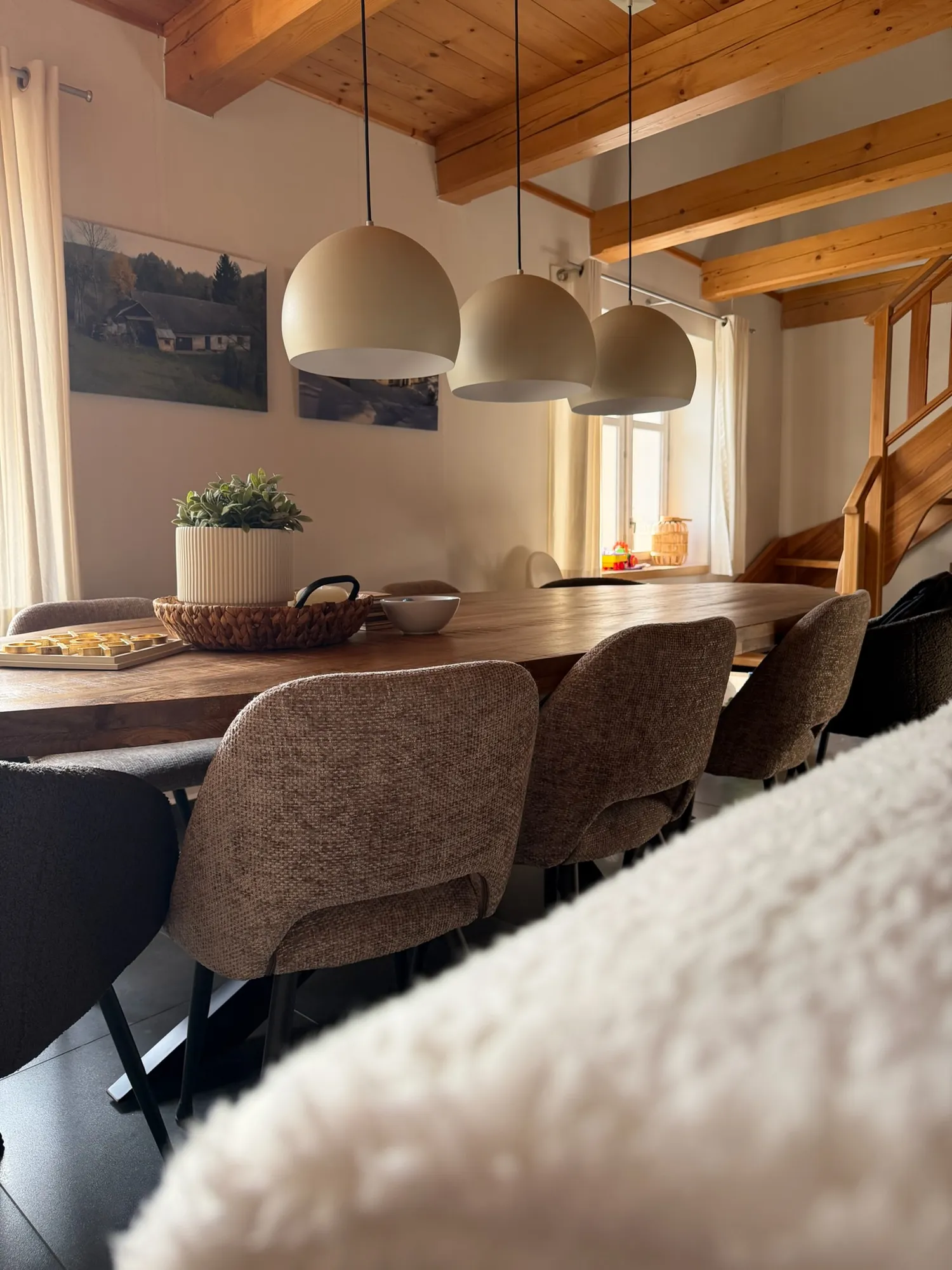 Lange houten eettafel voor de hele groep onder houten balken in Everpine Mountain Lodge