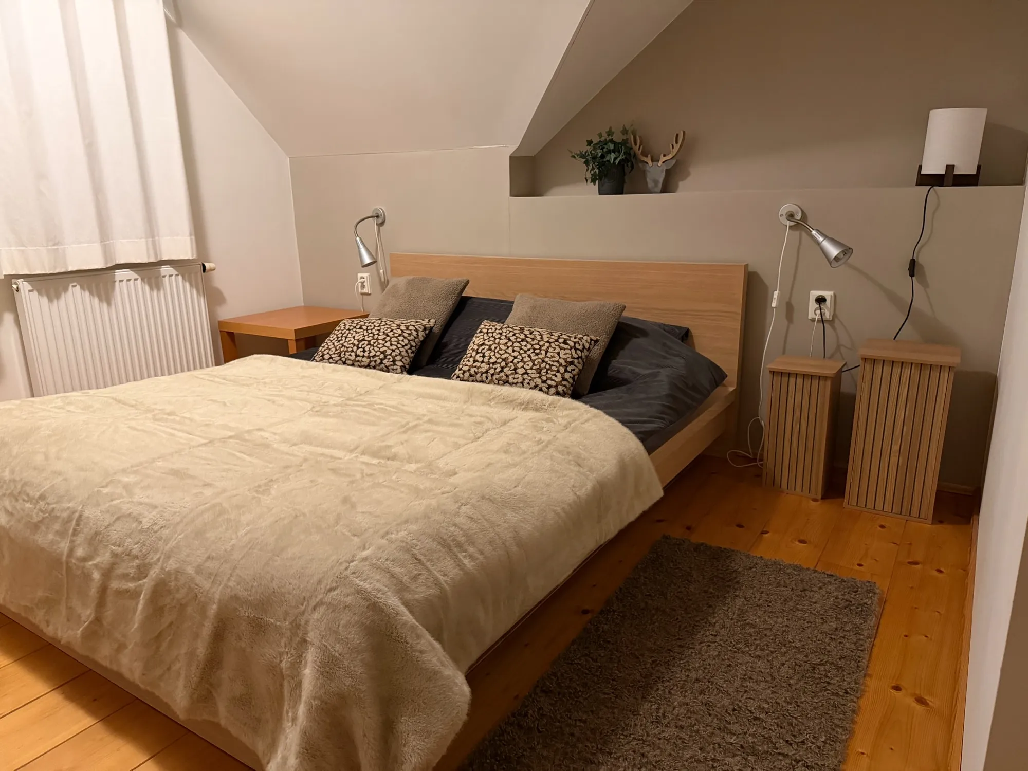 Slaapkamer onder het schuine dak met tweepersoonsbed, nachtkastjes en houten vloer