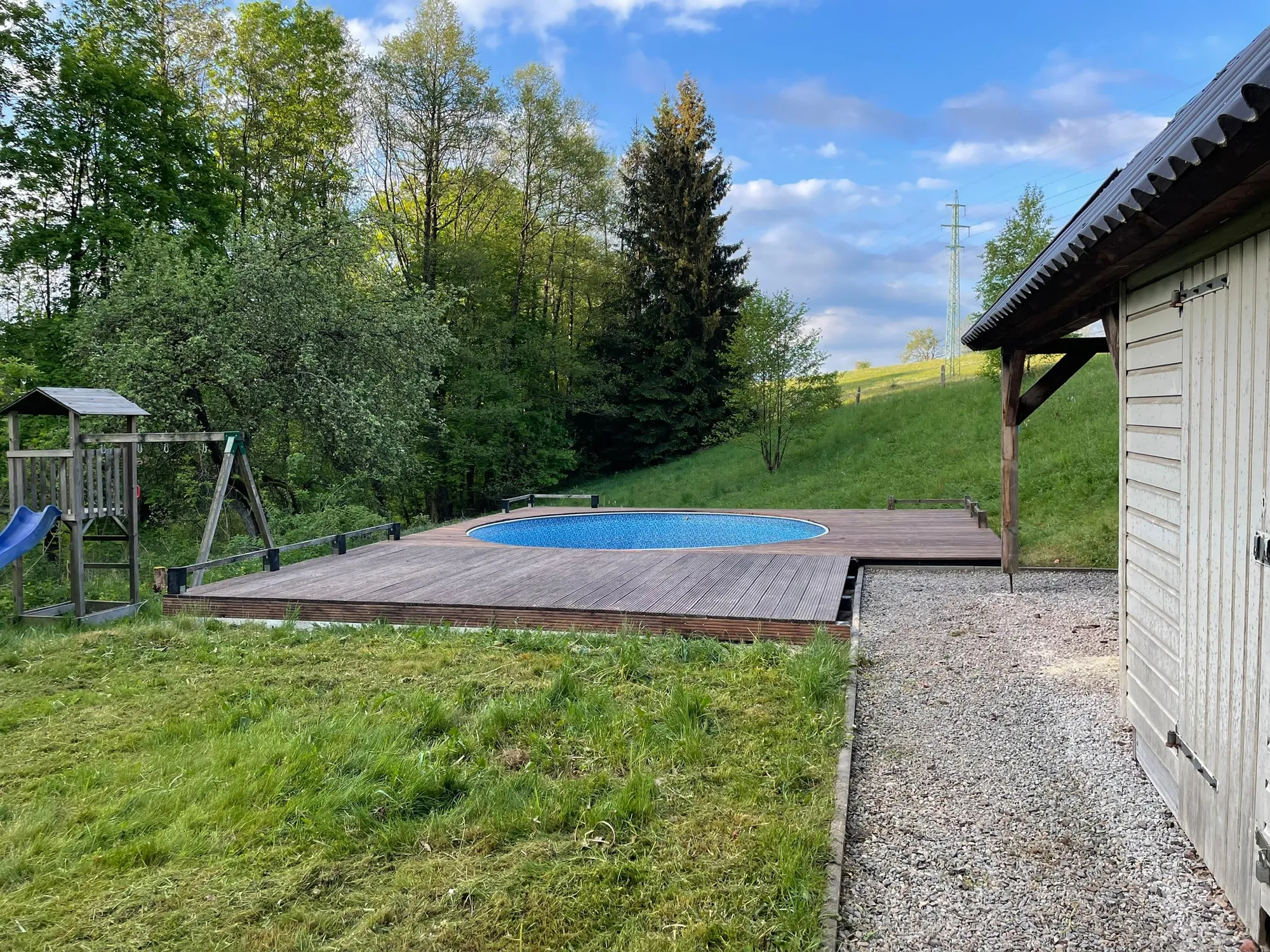 Tuin van Everpine Mountain Lodge met rond zwembad op een houten terras en speeltoestel voor kinderen