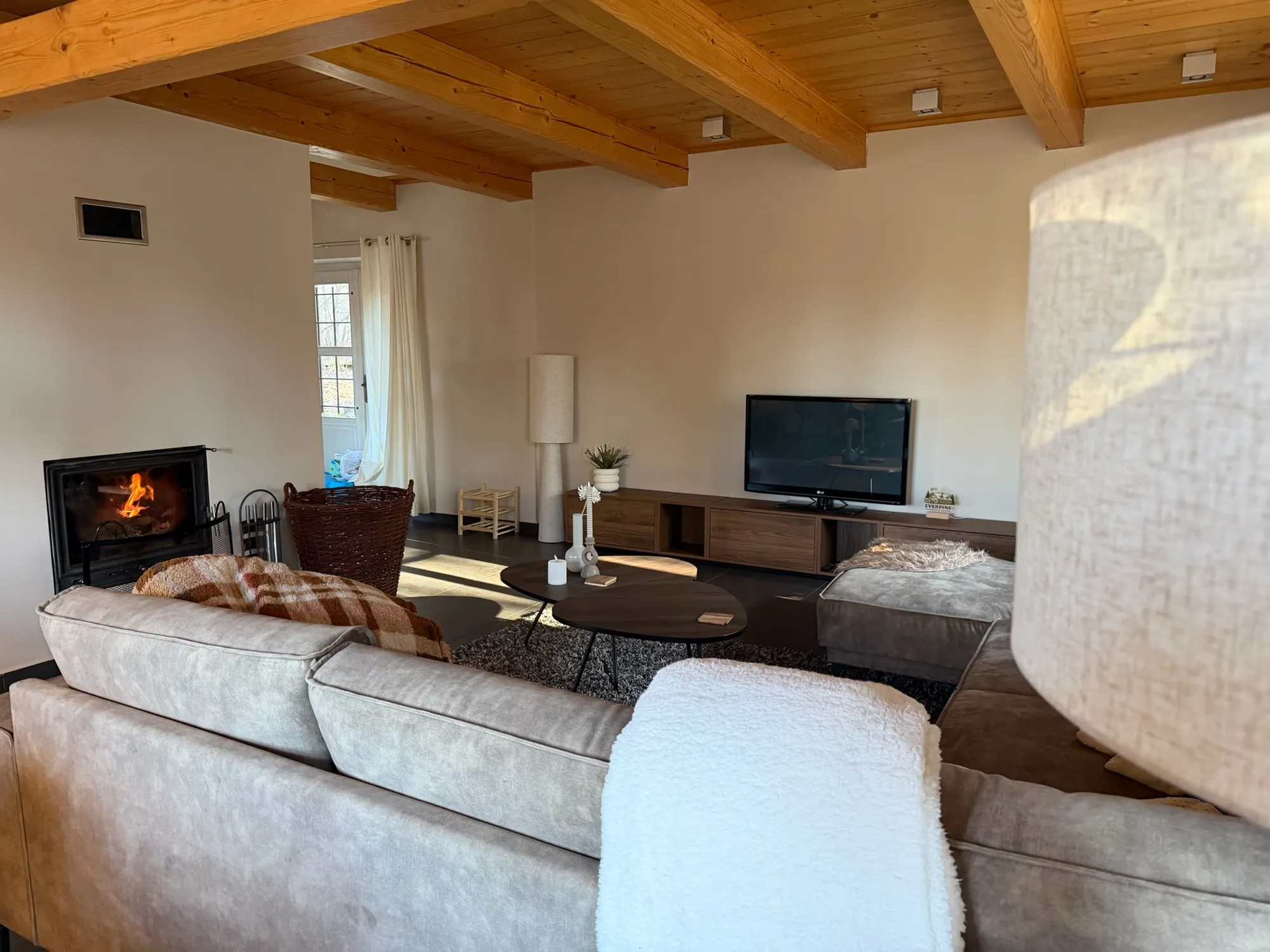 Ruime woonkamer met houten balkenplafond, haard en zithoek in Everpine Mountain Lodge